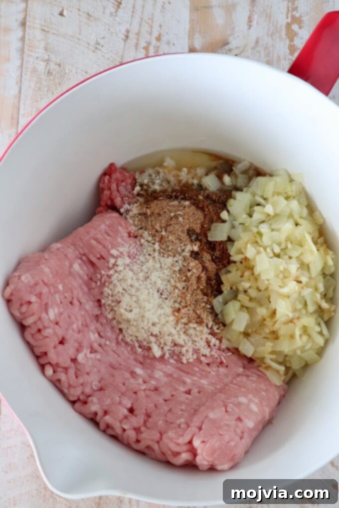 Perfect Air Fryer Meatloaf 4 raw ground beef and ground pork in a large mixing bowl with breadcrumbs, cooked onions, and spices