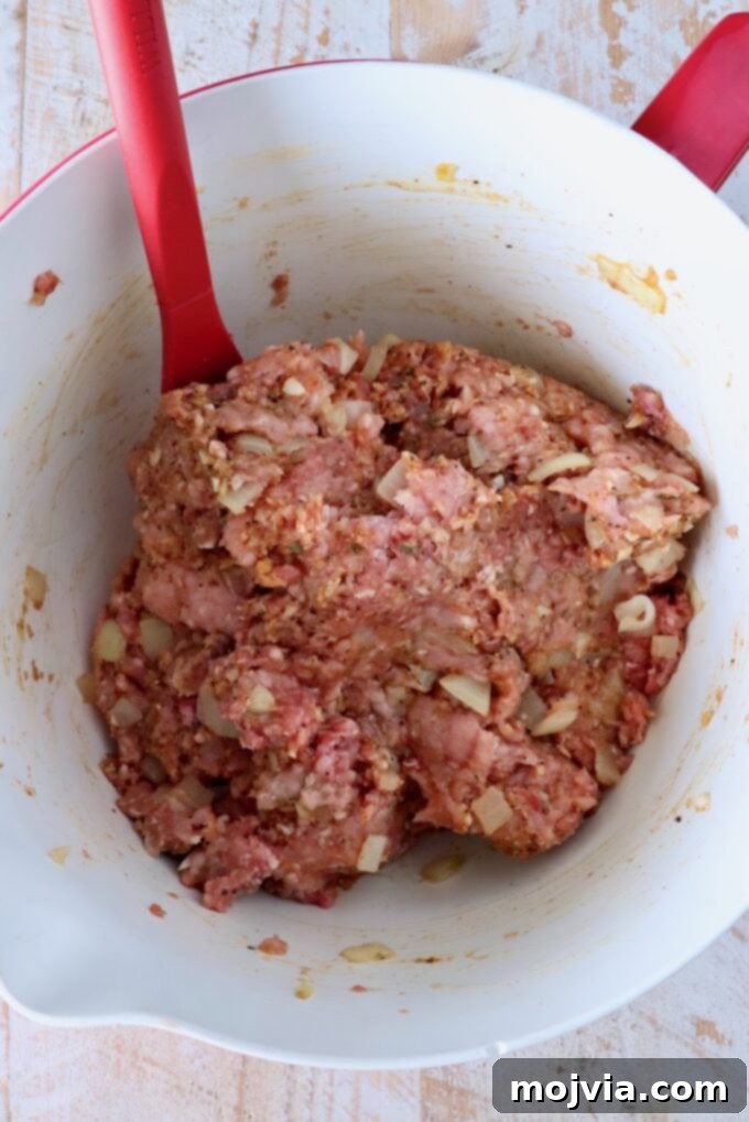 Perfect Air Fryer Meatloaf 5 meatloaf mixture combined in a mixing bowl with a red spatula