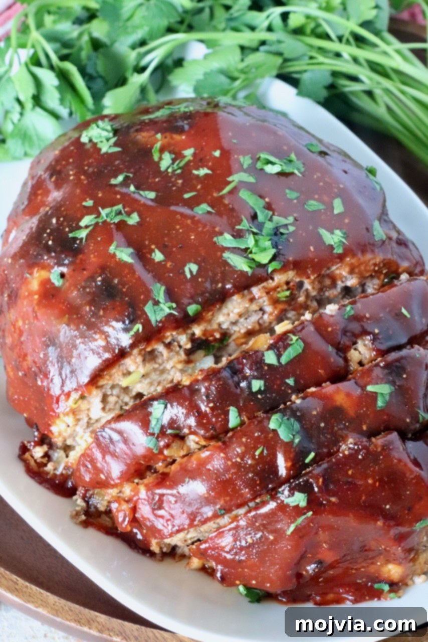Perfect Air Fryer Meatloaf 10 glazed cooked meatloaf sliced on a plate with fresh parsley