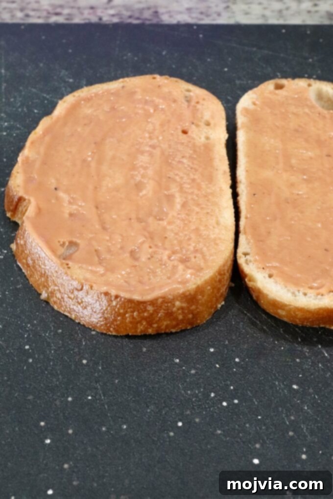 bbq mayonnaise spread on two slices of bread on a cutting board