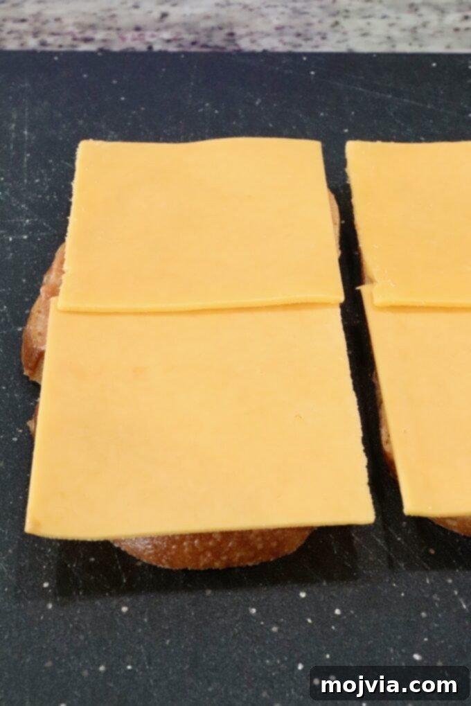 slices of cheddar cheese placed on two slices of bread on a cutting board