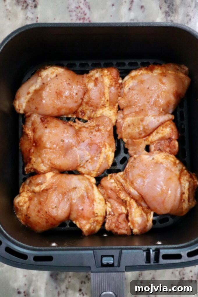 Sizzling Air Fryer Chicken Fajitas 5 Perfectly seasoned raw chicken thighs arranged in a single layer inside an air fryer basket, ready for cooking.