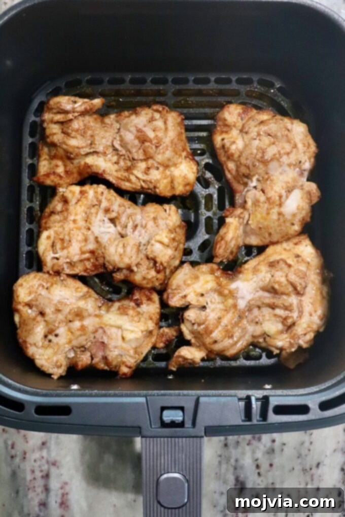 Sizzling Air Fryer Chicken Fajitas 6 Golden-brown, perfectly cooked and seasoned chicken thighs resting in an air fryer basket after cooking.