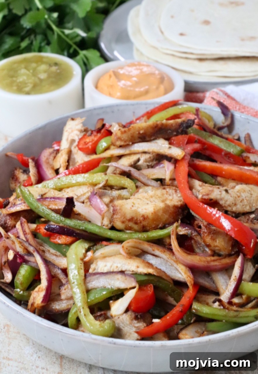 Sizzling Air Fryer Chicken Fajitas 10 A serving of cooked chicken fajitas, featuring perfectly sliced chicken, tender bell peppers, and onions, artfully arranged in a rustic bowl.