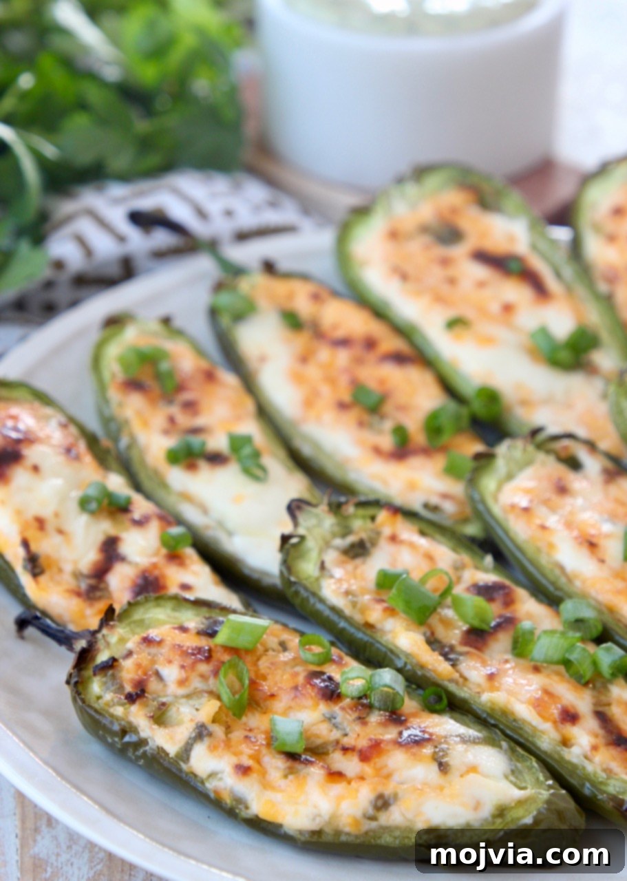 Smoky Cheesy Jalapeño Bites 2 Cheese stuffed grilled jalapenos on a plate, ready to be served at a BBQ or party.