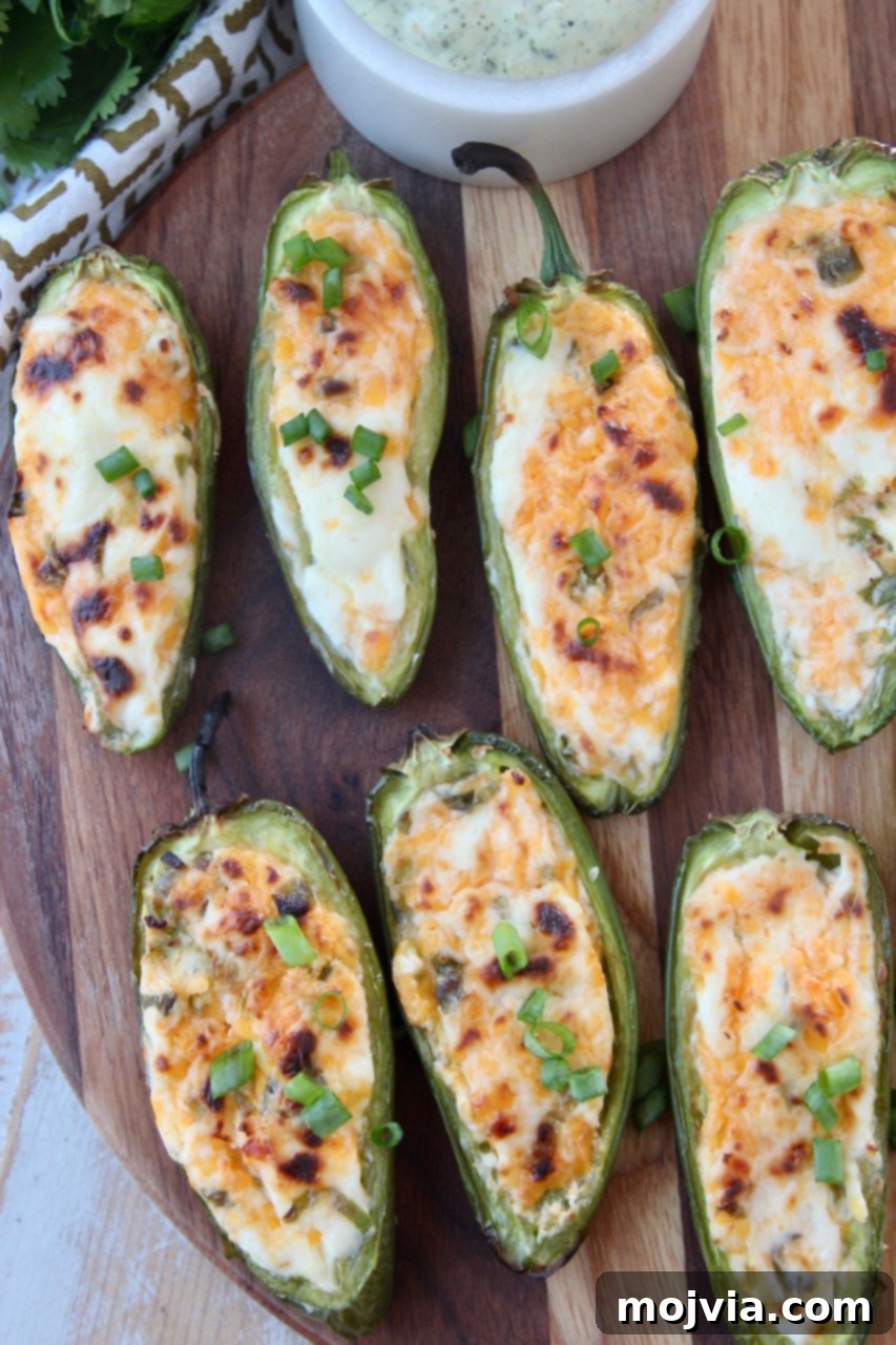 Smoky Cheesy Jalapeño Bites 6 Cooked grilled jalapeno poppers arranged on a wooden cutting board, garnished with fresh herbs.
