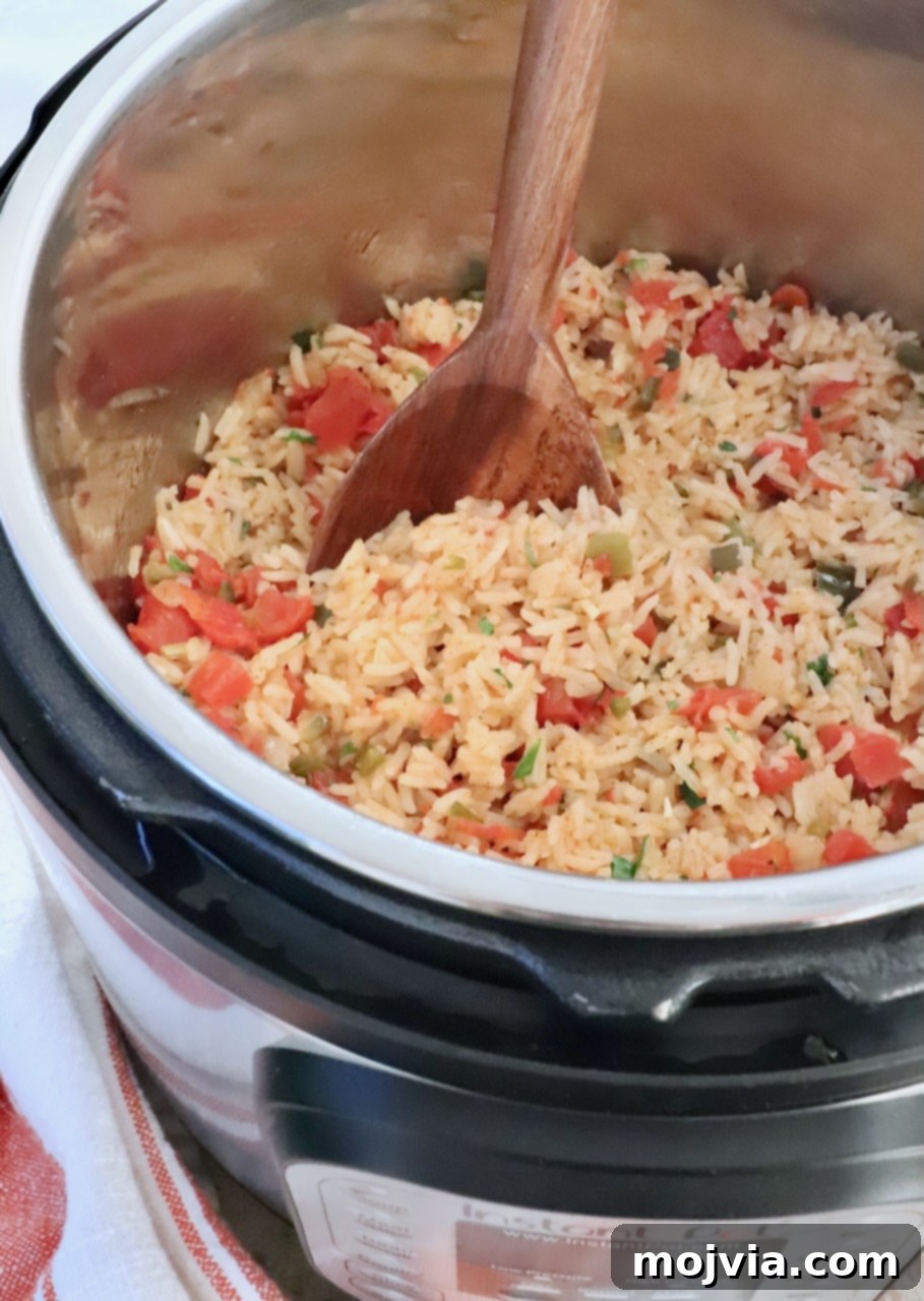Speedy Instant Pot Mexican Rice 2 Cooked Mexican rice in an Instant Pot, perfectly fluffy and ready to serve, with a large wooden spoon