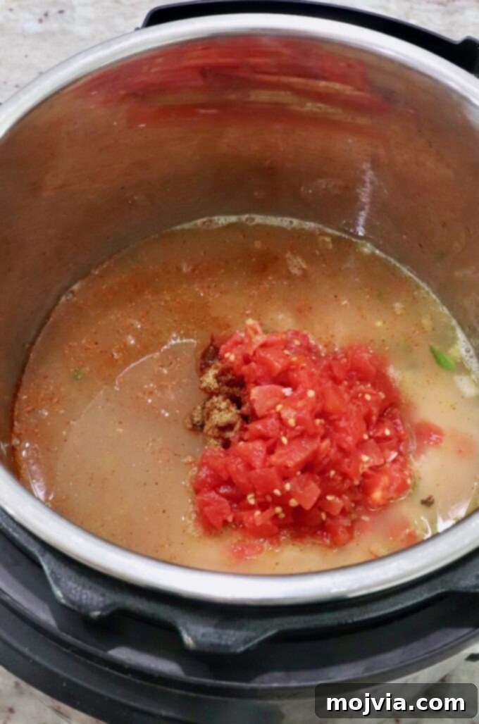 Speedy Instant Pot Mexican Rice 5 Diced tomatoes being added to the Instant Pot with sautéed vegetables, rice, and broth