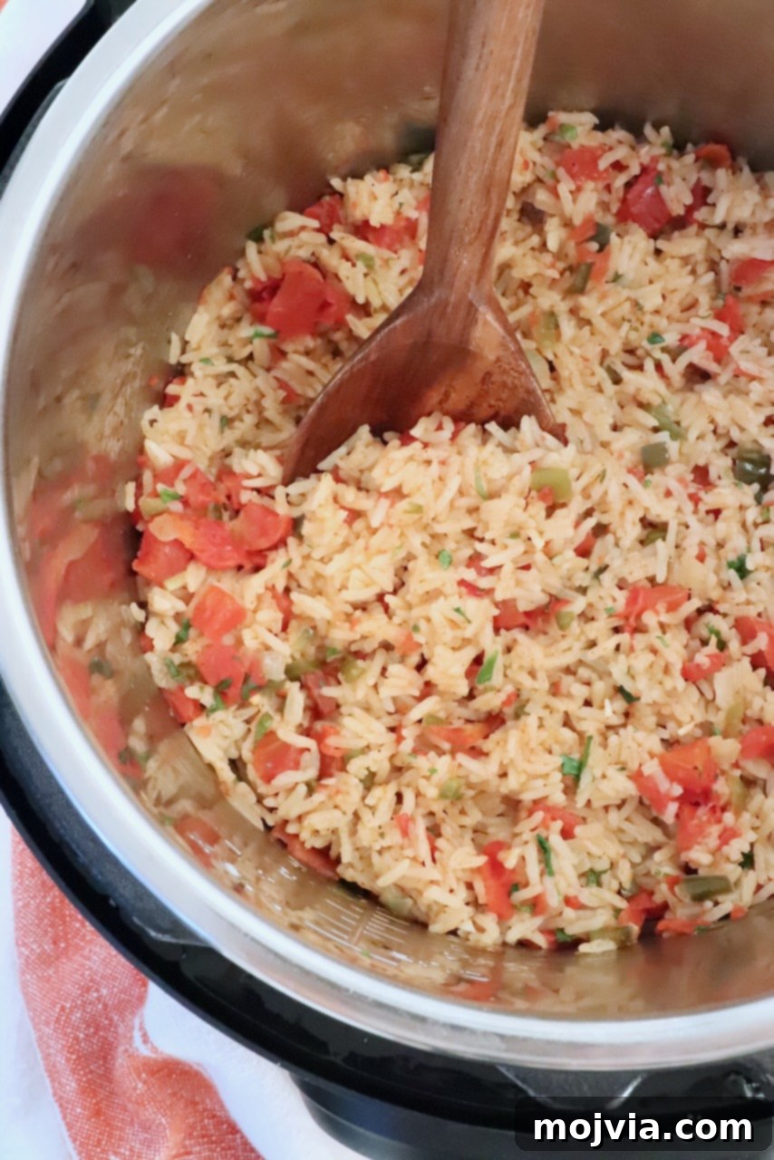 Speedy Instant Pot Mexican Rice 9 A close-up of fluffy Mexican rice inside an Instant Pot, with a wooden spoon scooping out a serving