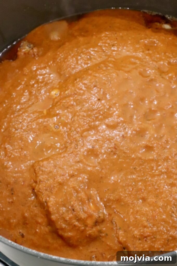 Chicken thighs covered in adobo sauce in a large Dutch oven