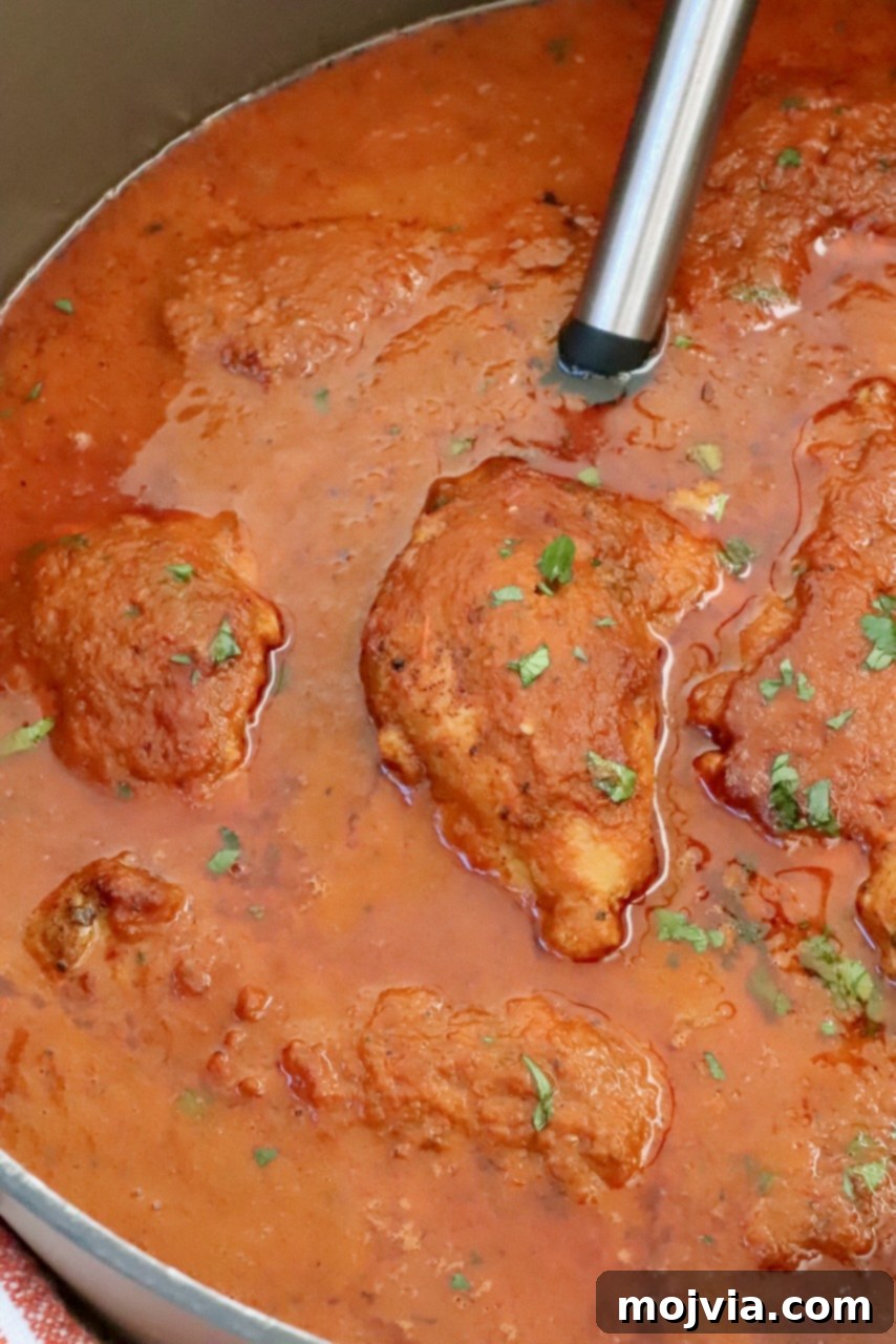 Chicken covered in adobo sauce in a large pot with a serving spoon