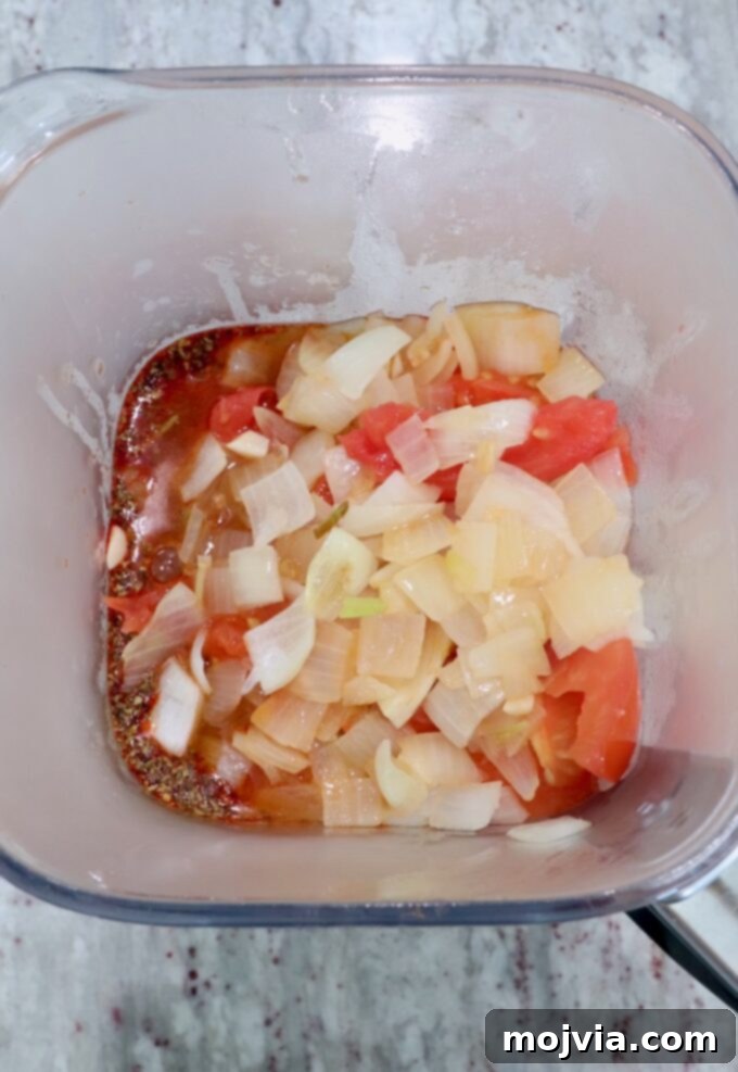 Cooked onions and tomatoes in a blender with other adobo sauce ingredients