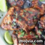 Chipotle Honey Glazed Chicken 12 grilled chicken thighs stacked up on a plate with fresh cilantro and lime wedges