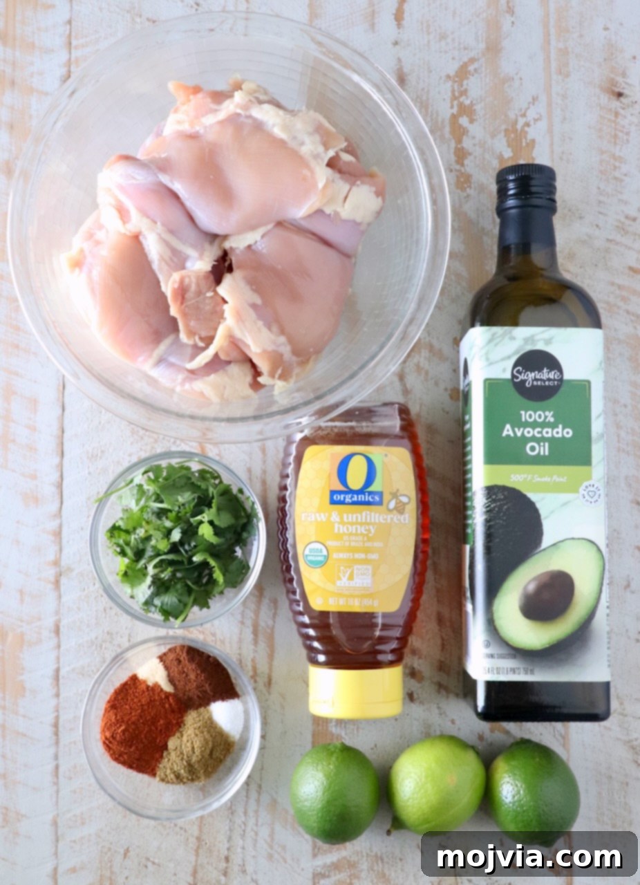 Chipotle Honey Glazed Chicken 3 fresh ingredients for chipotle honey chicken, including chicken, honey, lime, and spices, arranged on a rustic wood board