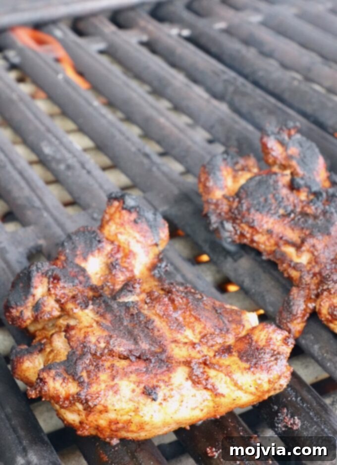 Chipotle Honey Glazed Chicken 8 grilled chicken thighs cooking on the grill, showing slight char marks