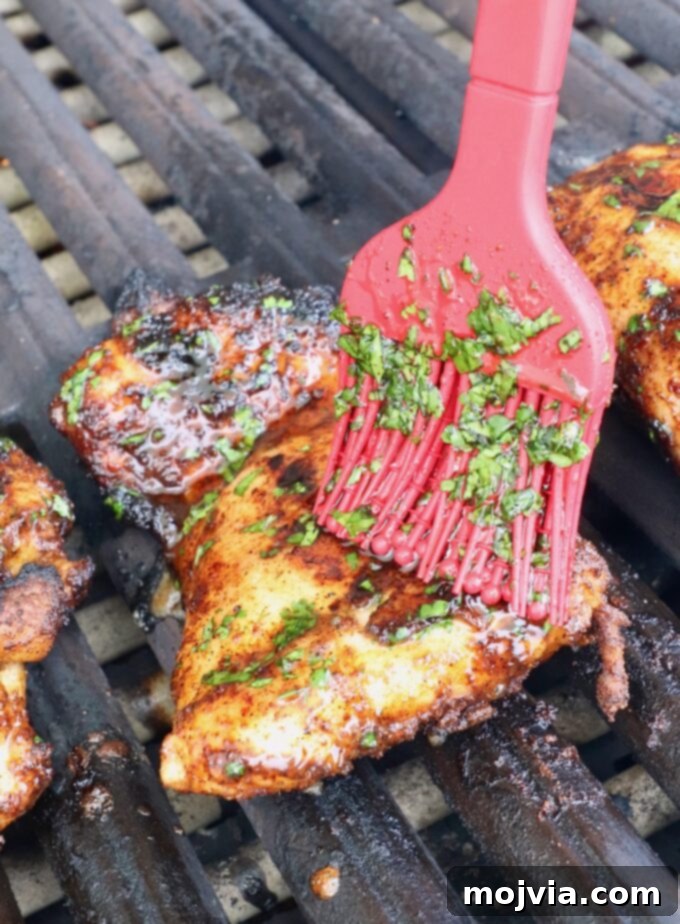 Chipotle Honey Glazed Chicken 9 a red brush applying cilantro honey glaze to a piece of grilled chicken on the grill