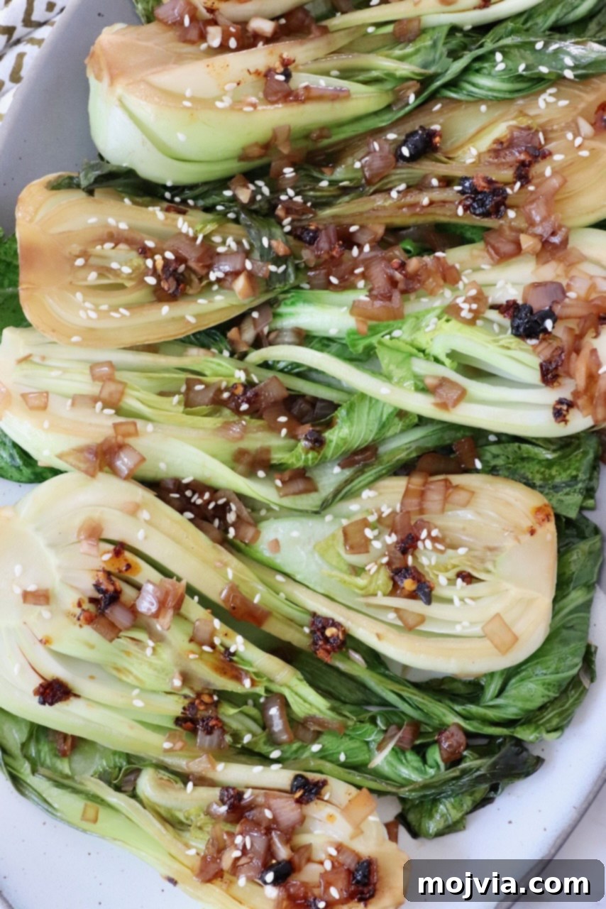 Petite Bok Choy 2 cooked baby bok choy topped with garlic shallot soy sauce on a plate