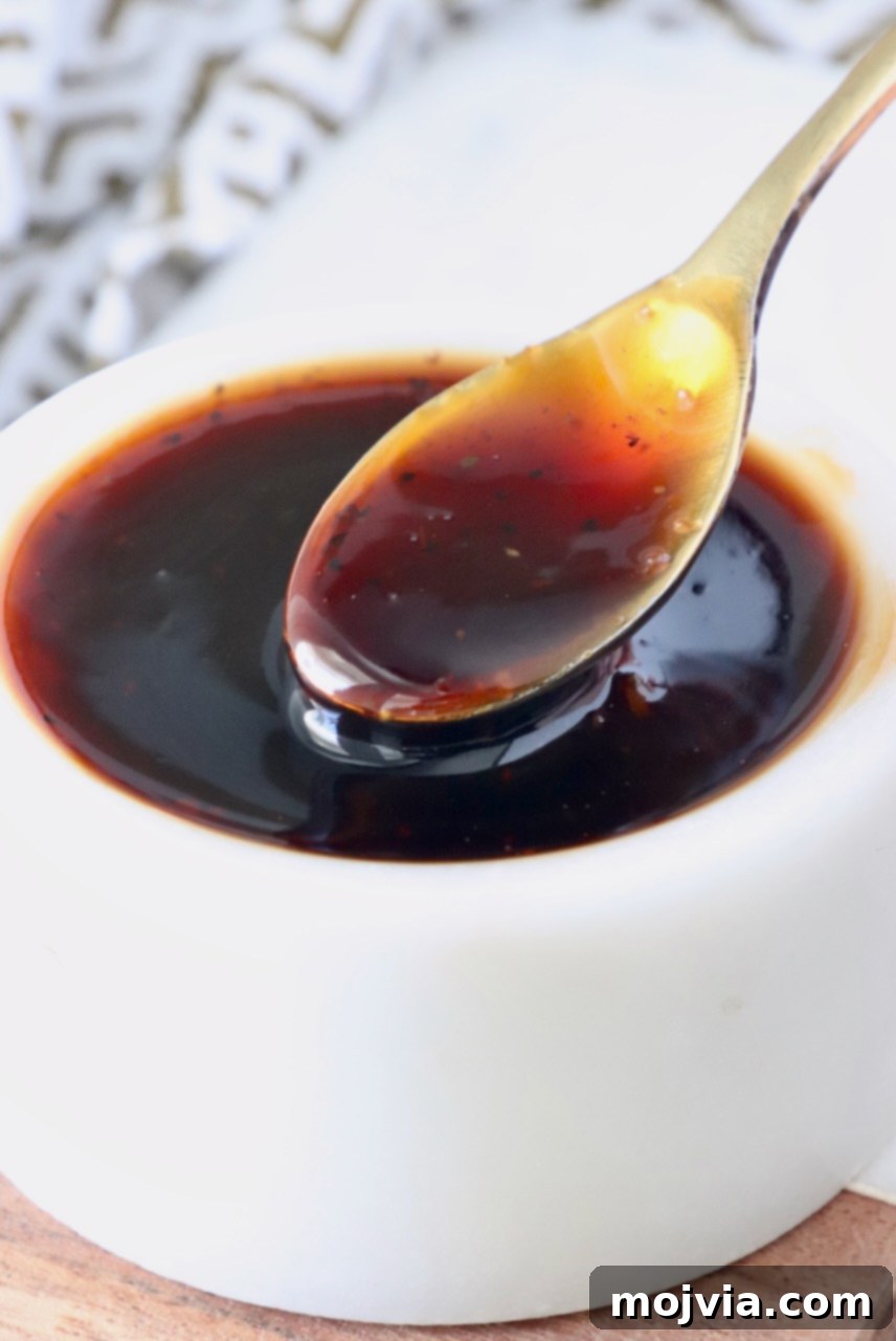 Authentic Korean BBQ Sauce 7 A small, elegant white bowl filled with glossy Korean BBQ sauce, with a tiny silver spoon resting in the sauce, inviting a taste.
