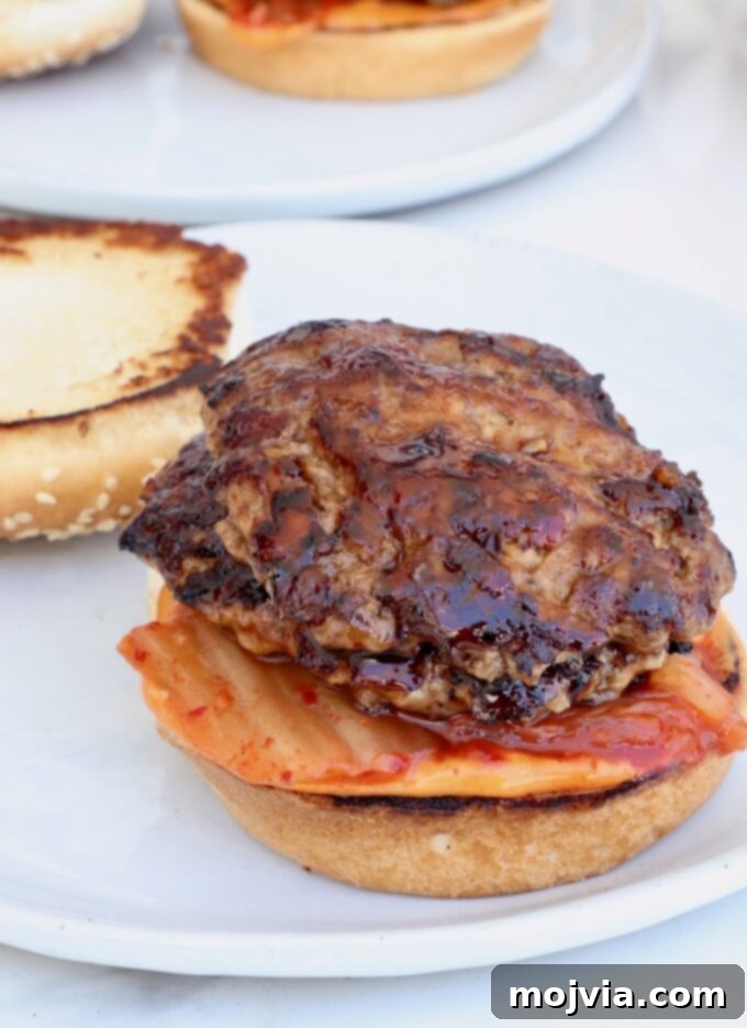 Assembled hamburger bun with kimchi and two Korean BBQ glazed burger patties