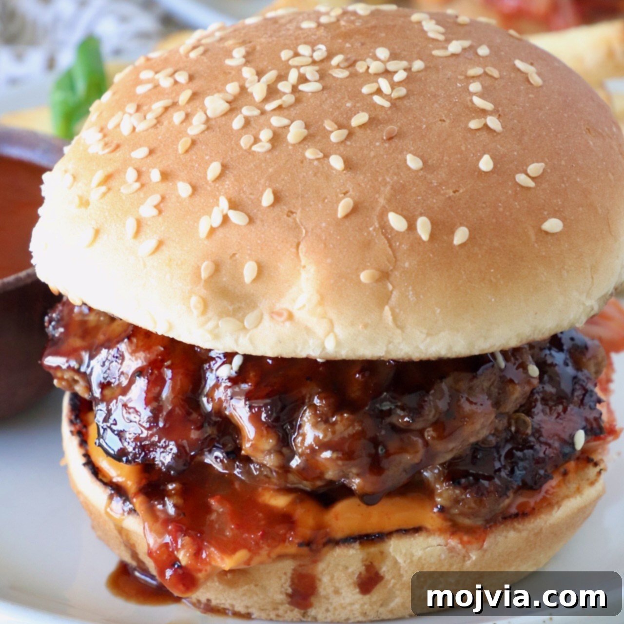Prepared Korean BBQ Burger on a plate with additional Korean BBQ sauce drizzled over it