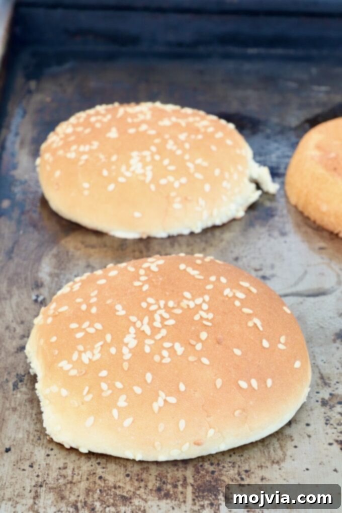 Sesame seed buns toasting on a hot griddle