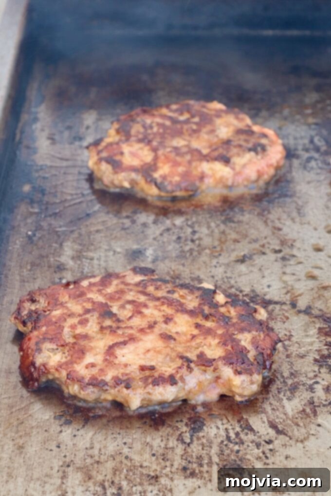 Multiple grilled burger patties sizzling on a griddle