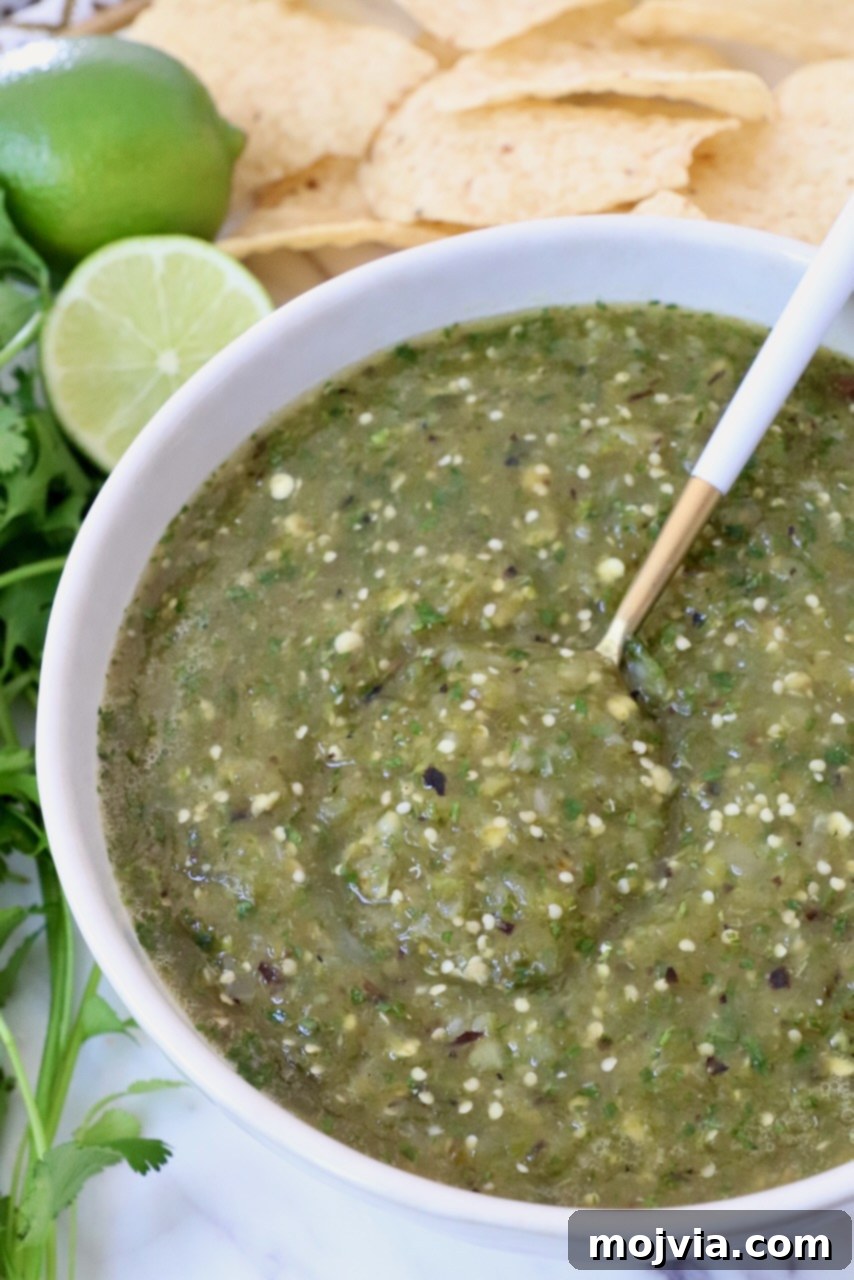 Verde Zing Salsa 2 Fresh homemade tomatillo salsa verde in a rustic bowl, garnished with a sprig of cilantro, ready to be served.