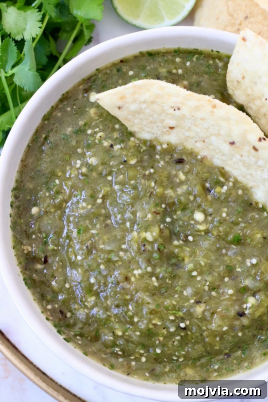 Verde Zing Salsa 9 A bowl of vibrant green salsa verde, perfectly chunky, surrounded by a pile of golden tortilla chips, ready for dipping.
