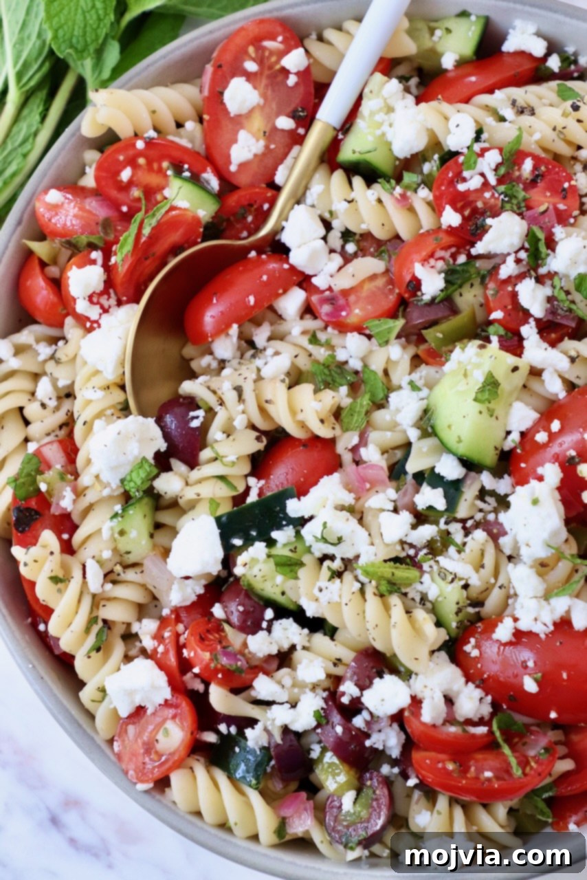 Aegean Breeze Pasta Medley 2 pasta salad with cucumber and tomatoes in a bowl with a spoon