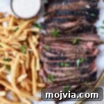 Sliced, grilled beef shawarma on a platter, accompanied by crispy french fries and a small bowl of creamy sauce, ready to be served.