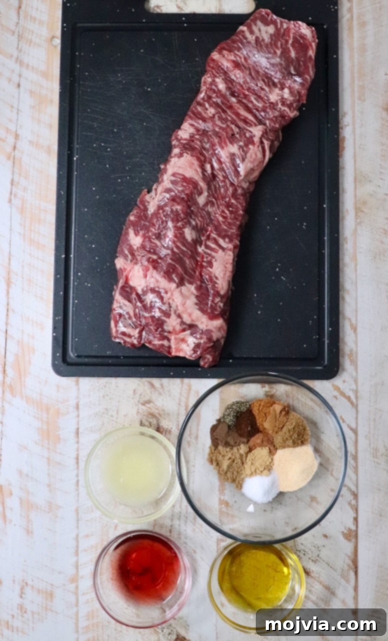 A selection of fresh ingredients for beef shawarma laid out on a white wooden board, including a vibrant skirt steak, fresh lemons, red wine vinegar, olive oil, and a bowl of rich, homemade shawarma seasoning.