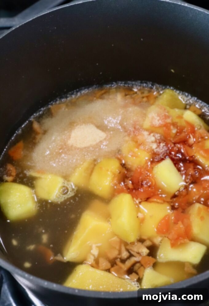 Diced mango, honey, apple cider vinegar, garlic powder, and minced habanero peppers simmering in a saucepan