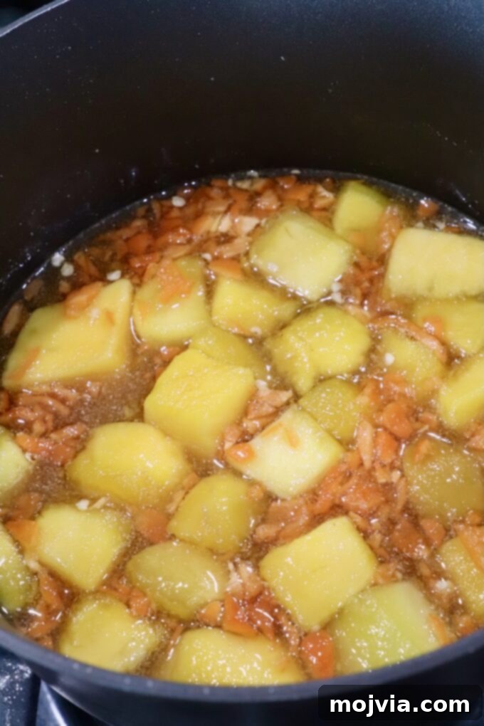 The mango habanero sauce mixture gently simmering in a saucepan on the stove