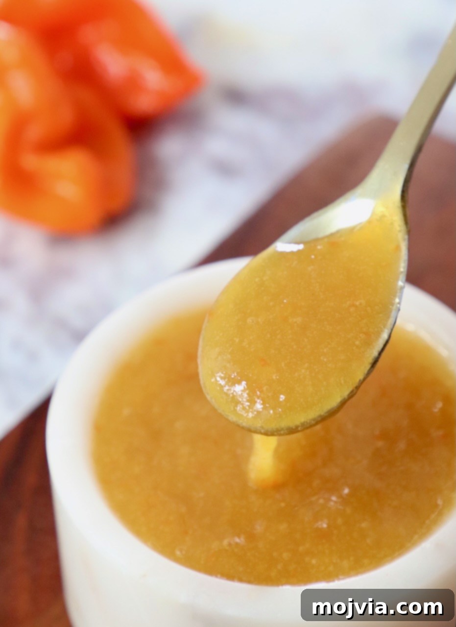 Homemade mango habanero sauce served in a spoon and a small bowl, showcasing its vibrant color and smooth texture