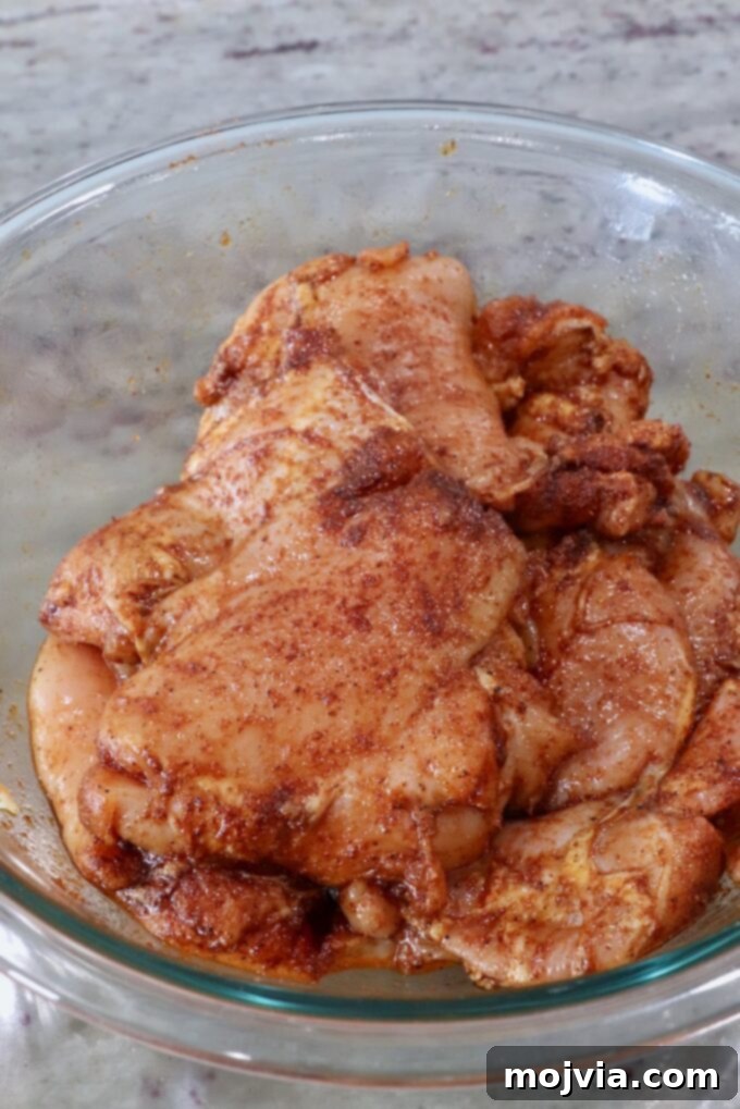 Perfectly Smoked Chicken Thighs 4 seasoned, raw chicken thighs in a glass bowl