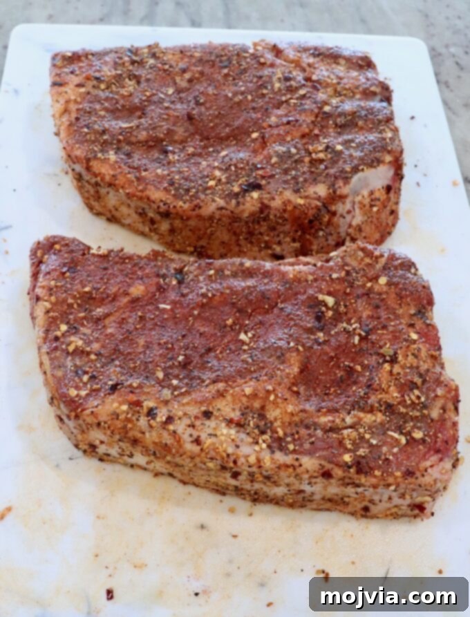 Air Fryer Steakhouse Steak 4 seasoned ribeye steaks on a cutting board