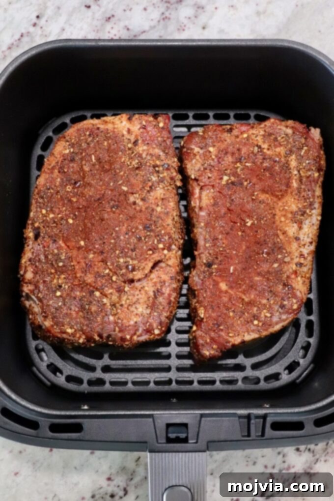 Air Fryer Steakhouse Steak 5 seasoned ribeye steaks in an air fryer basket