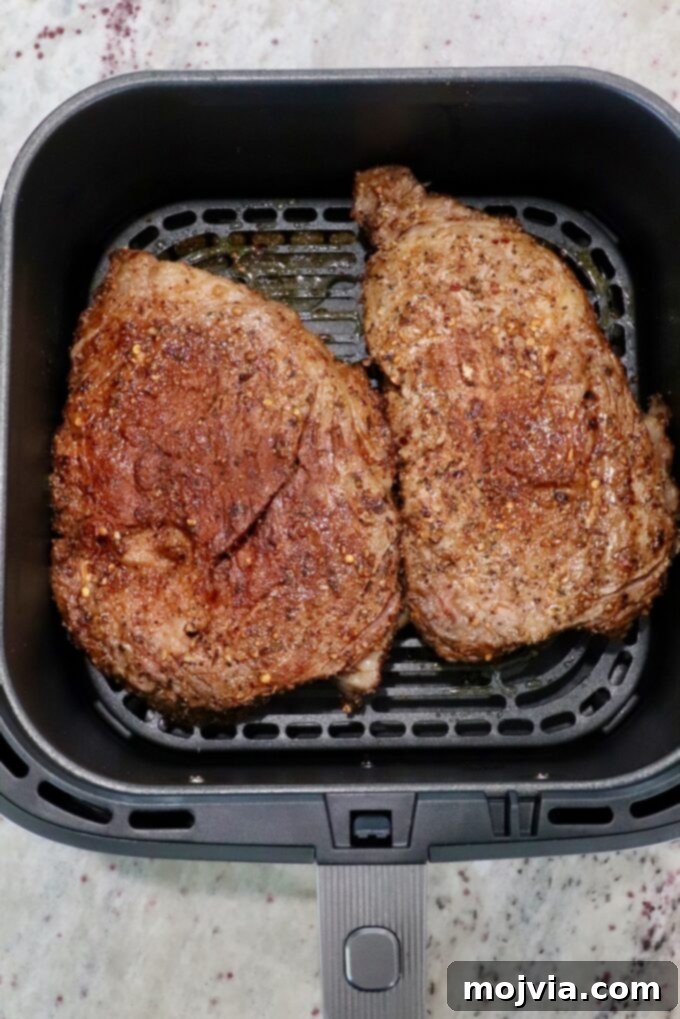 Air Fryer Steakhouse Steak 6 seasoned ribeye steaks in an air fryer basket