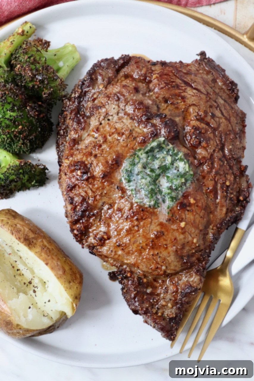 Air Fryer Steakhouse Steak 8 cooked ribeye steak on a plate with a fork, baked potato and cooked broccoli
