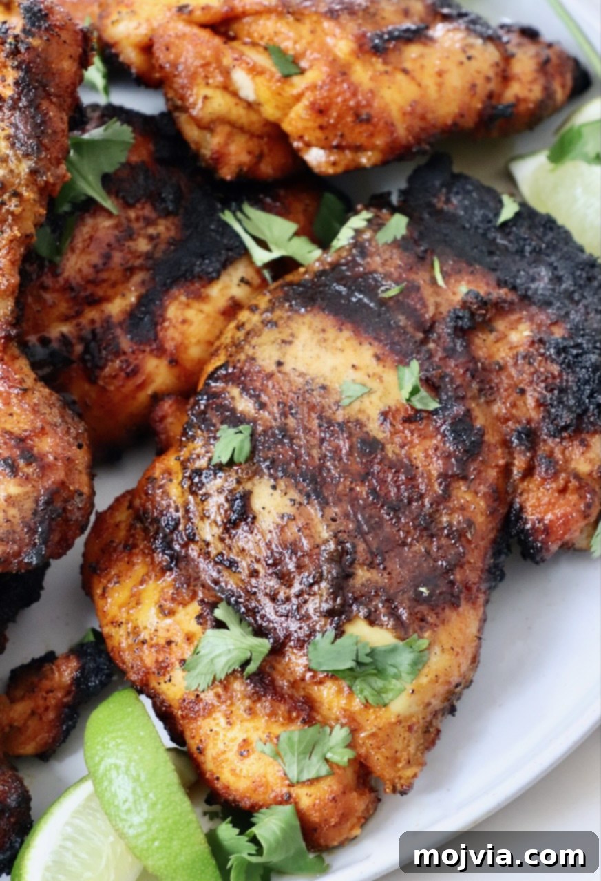Sazon Spice Blend 4 grilled chicken thighs stacked up on a plate with lime wedges on the side