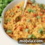 yellow rice in a bowl with a spoon and fresh cilantro