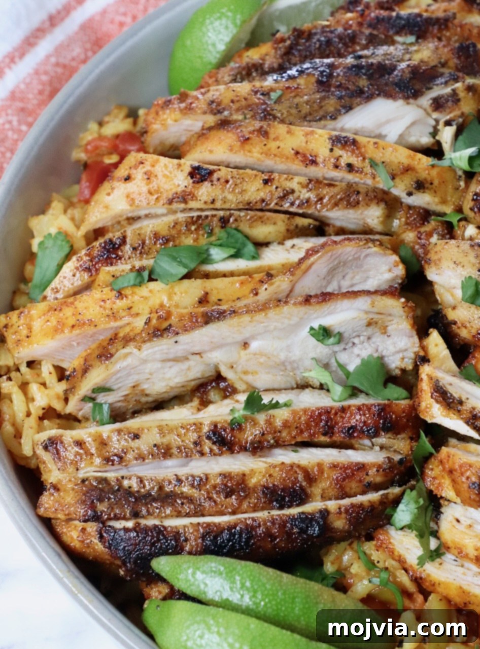 sliced grilled chicken thighs in a bowl with rice and lime wedges