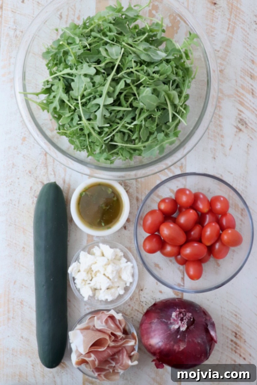 Refreshing Prosciutto Arugula Cucumber Salad 3 Fresh ingredients laid out for Prosciutto Salad on a white wooden board