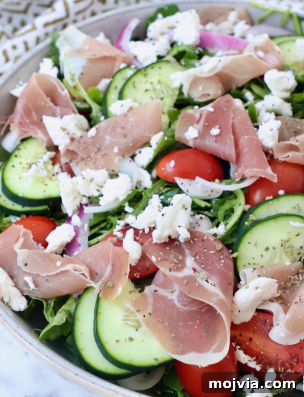 Refreshing Prosciutto Arugula Cucumber Salad 4 Close-up of Prosciutto Salad with cucumber, tomatoes, and feta on top of arugula