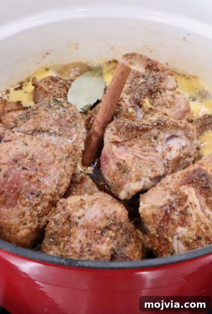 Pork Carnitas 6 seasoned pieces of pork in a large cast iron dutch oven with liquid, cinnamon sticks and bay leaves