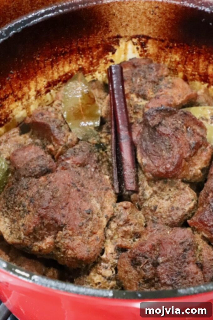 Pork Carnitas 7 cooked pieces of pork in a large cast iron dutch oven with a cinnamon stick and bay leaves
