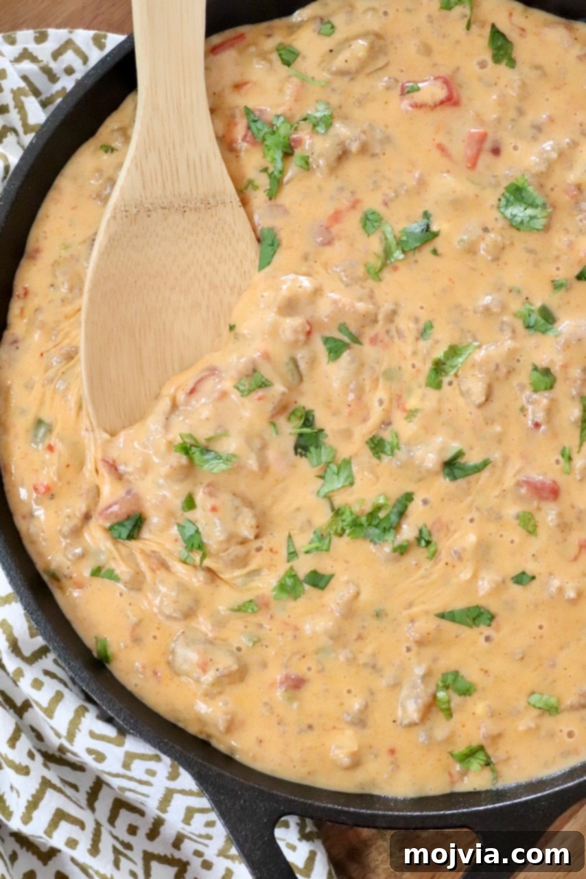 Creamy Smoked Queso 2 smoked queso dip in a skillet with a wooden spoon