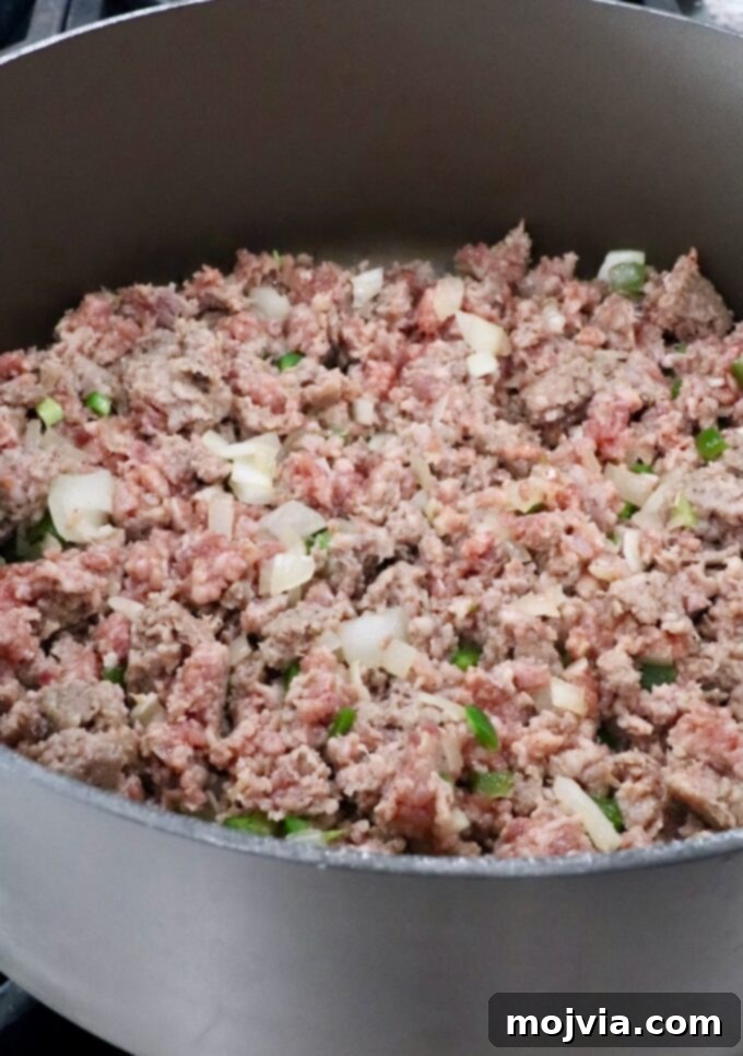 Creamy Smoked Queso 5 cooked sausage in a large pot with diced onions and jalapenos