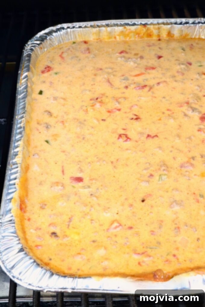 Creamy Smoked Queso 9 queso dip in an aluminum pan on a smoker