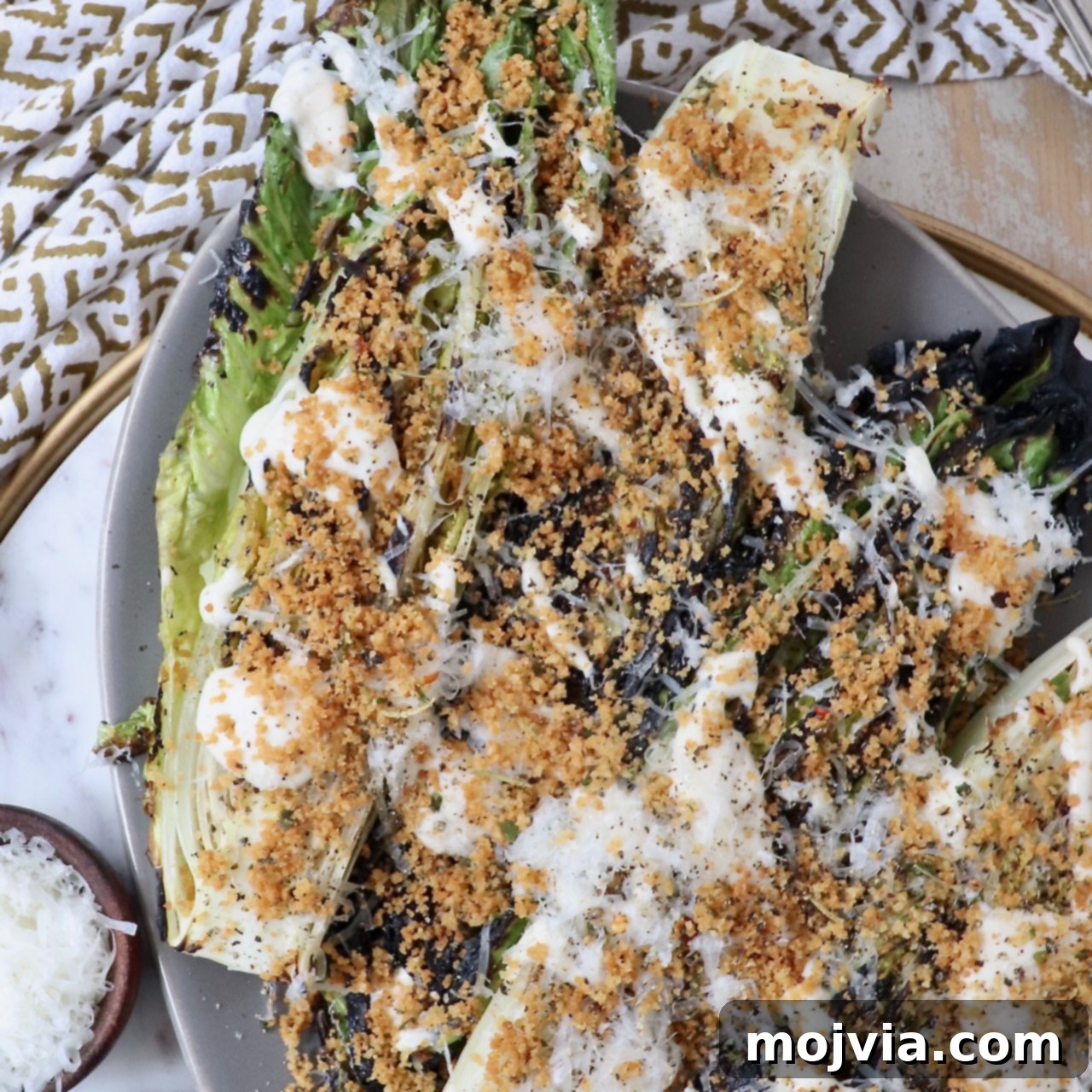 A delectable Grilled Caesar Salad on a plate, featuring lightly charred romaine lettuce, generously topped with crispy toasted breadcrumbs and a creamy dressing.